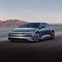 سيارة Lucid Air Pure باللون الأزرق فاثوم المعدني تسير على طول الساحل.