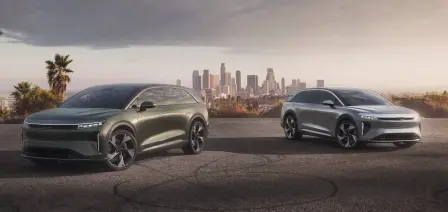An Aurora Green Metallic Lucid Gravity and a Lunar Titanium Metallic Lucid Gravity with a city scape in the background.