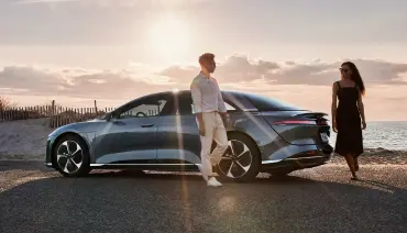 A couple coming out of a Lucid Air at the beach before sunset.
