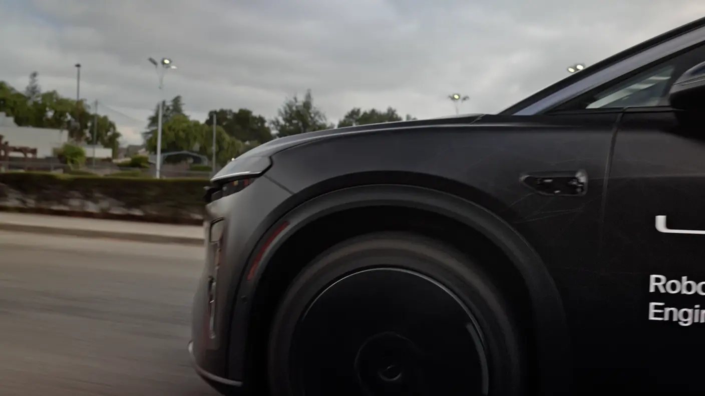 Close-up of a matte black autonomous vehicle's front wheel and fender, with "Robo" and "Engin" text visible on its side.