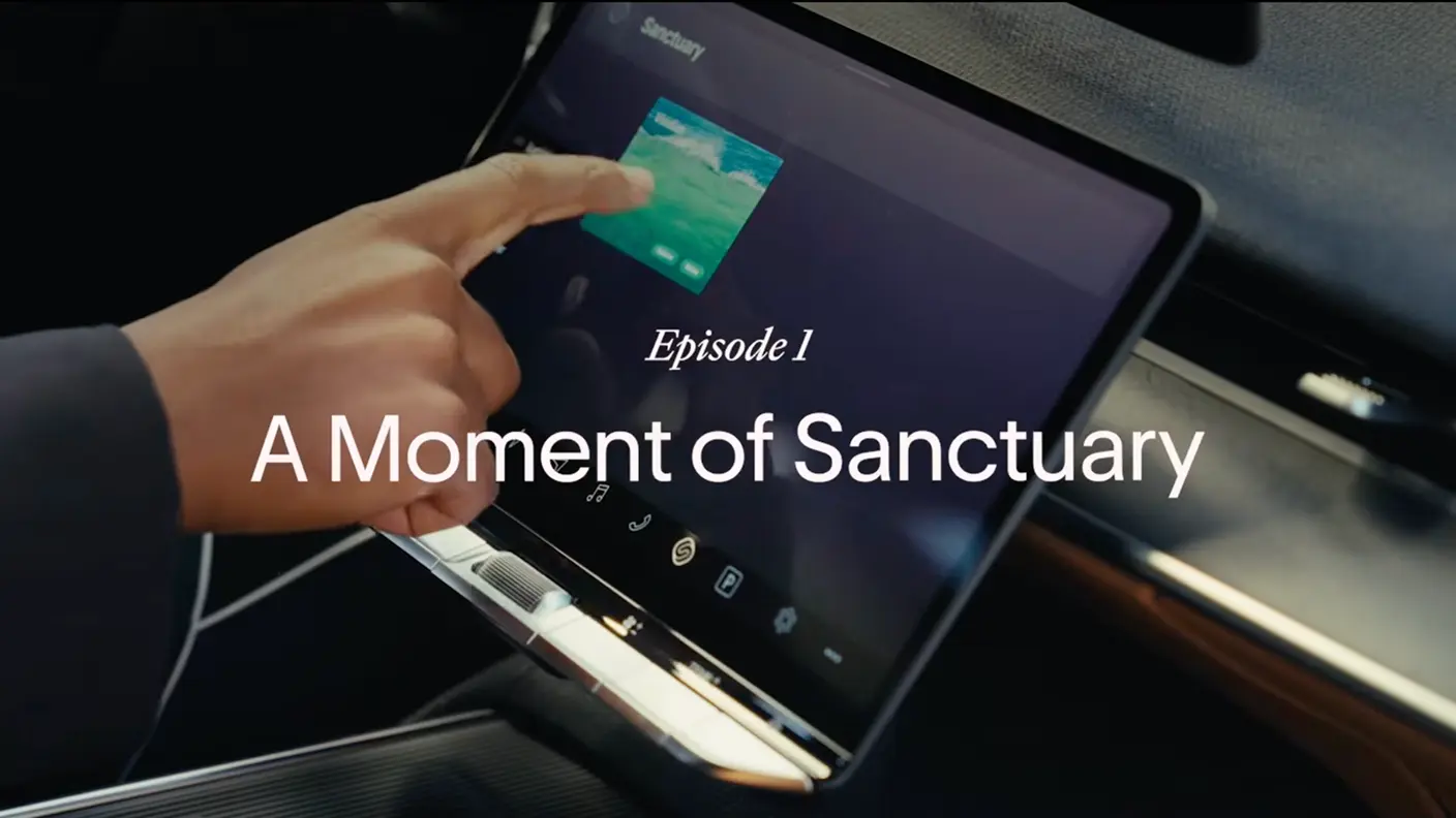 A hand tapping a car's touchscreen display, with text overlay reading "Episode 1: A Moment of Sanctuary."