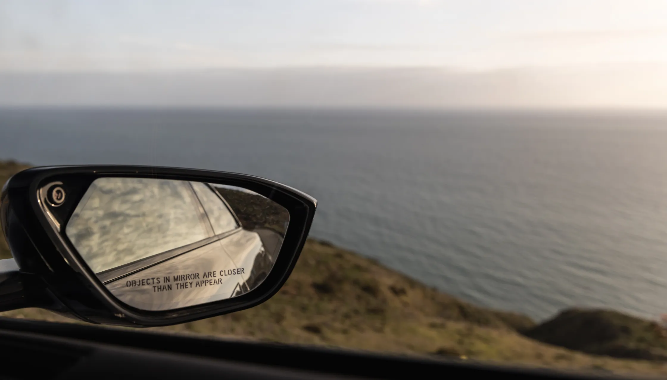 Side mirror of a Lucid Air driving by bay